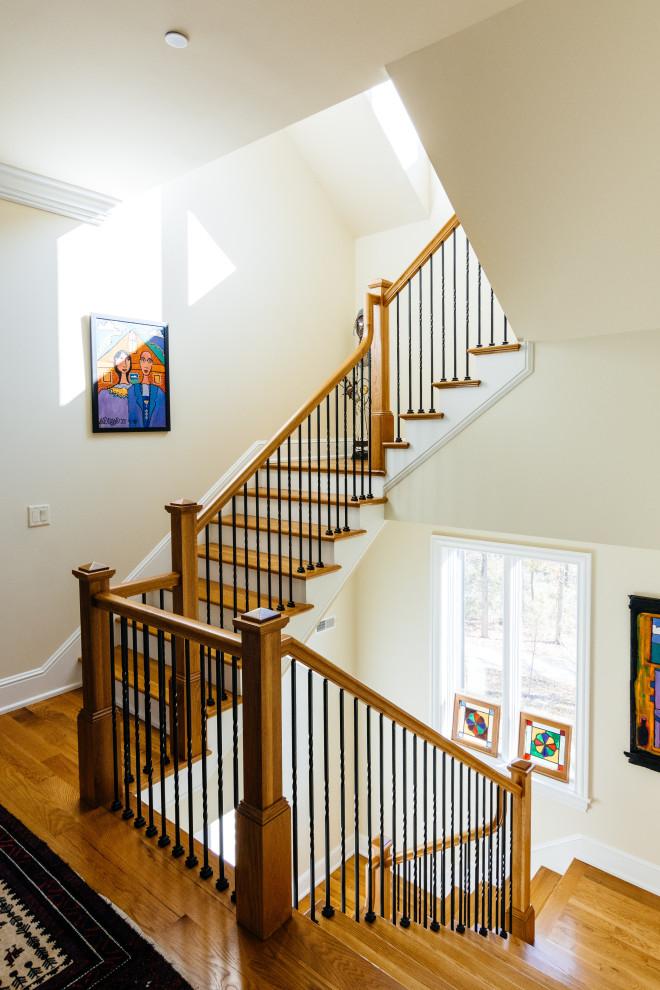 Diseño de escalera en U de estilo americano grande con escalones de madera, contrahuellas de madera pintada y barandilla de varios materiales