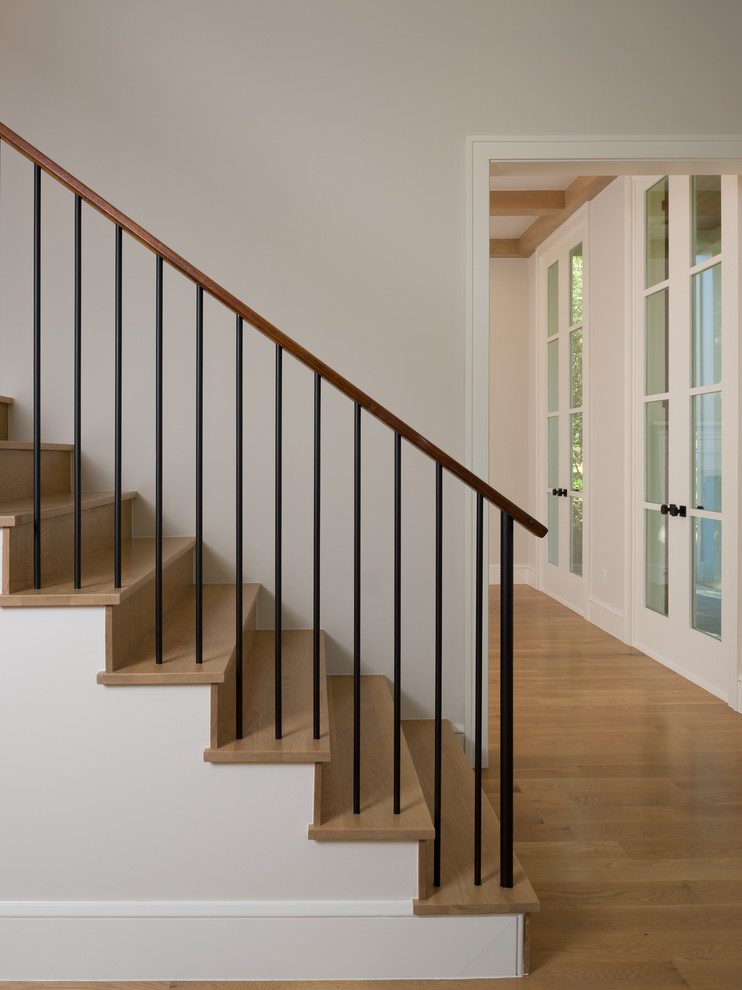 Diseño de escalera tradicional renovada con escalones de madera, contrahuellas de madera y barandilla de metal