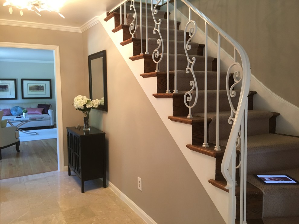 This is an example of a large traditional carpeted curved metal railing staircase in DC Metro with carpeted risers.