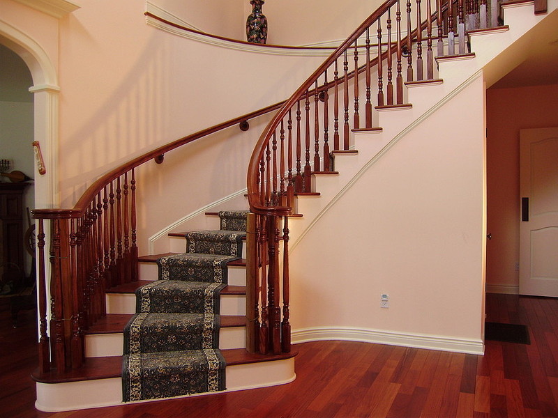Diseño de escalera curva clásica de tamaño medio con escalones enmoquetados, contrahuellas de madera y barandilla de madera