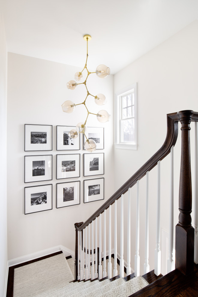 На фото: п-образная лестница в стиле неоклассика (современная классика) с ступенями с ковровым покрытием, ковровыми подступенками и деревянными перилами