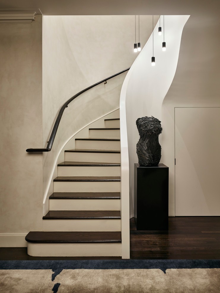 Classic wood curved staircase in London with painted wood risers.