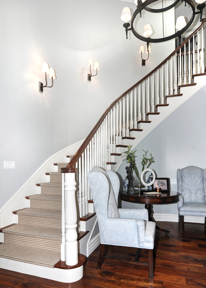 На фото: изогнутая лестница среднего размера в стиле кантри с ступенями с ковровым покрытием и ковровыми подступенками с