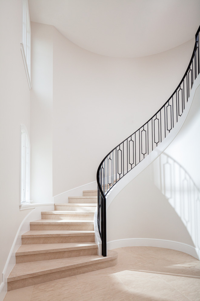 Design ideas for a large classic curved metal railing staircase in Orange County with limestone treads and limestone risers.