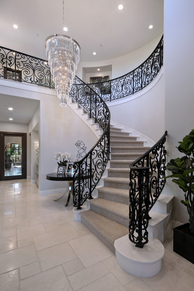 На фото: большая изогнутая лестница в современном стиле с ступенями с ковровым покрытием, ковровыми подступенками и металлическими перилами с