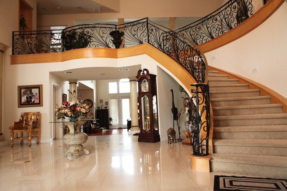 На фото: изогнутая лестница среднего размера в классическом стиле с металлическими ступенями и ковровыми подступенками