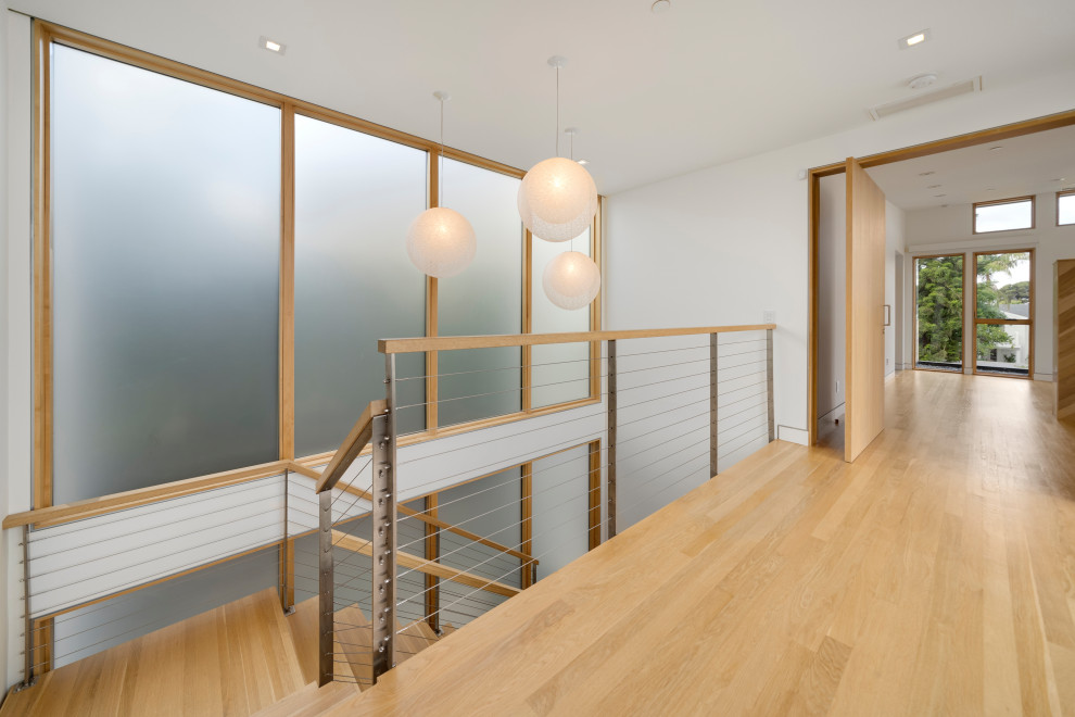 Photo of a large contemporary wood u-shaped wire cable railing staircase in Orange County with open risers.