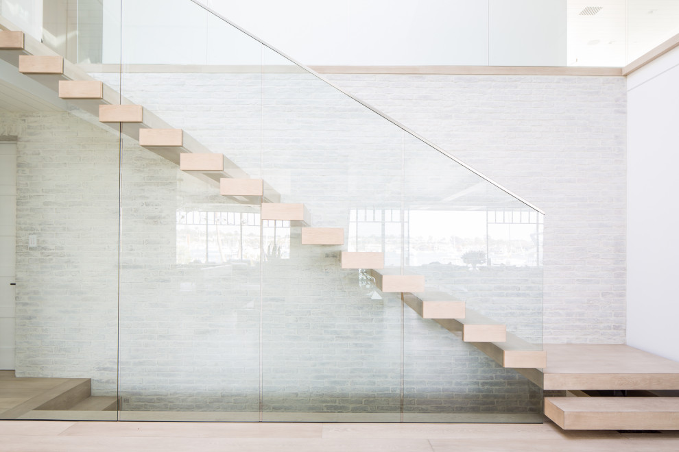 Источник вдохновения для домашнего уюта: огромная лестница на больцах в морском стиле с деревянными ступенями и стеклянными перилами
