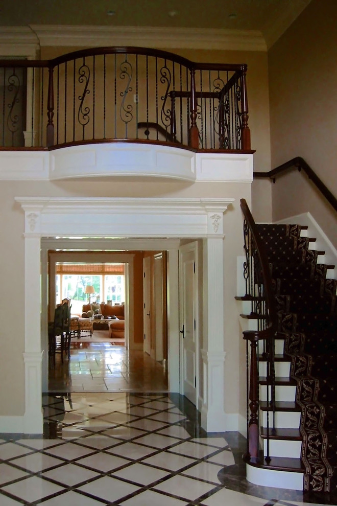 Large elegant wooden curved wood railing staircase photo in Boston with painted risers
