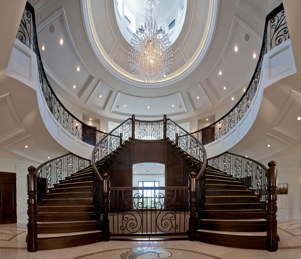 Идея дизайна: огромная изогнутая деревянная лестница в классическом стиле с деревянными ступенями