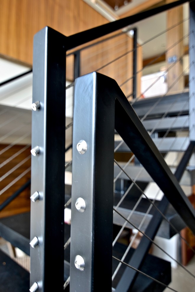 Immagine di una grande scala sospesa design con pedata in legno, alzata in metallo e parapetto in cavi