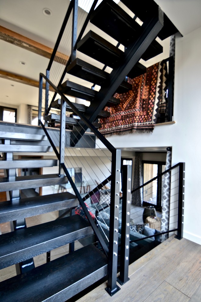 Idéer för att renovera en stor funkis flytande trappa i trä, med sättsteg i metall och kabelräcke