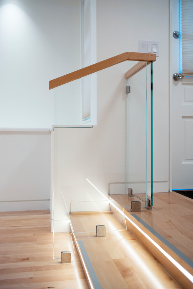 Ejemplo de escalera recta contemporánea pequeña con escalones de madera, contrahuellas de madera y barandilla de vidrio