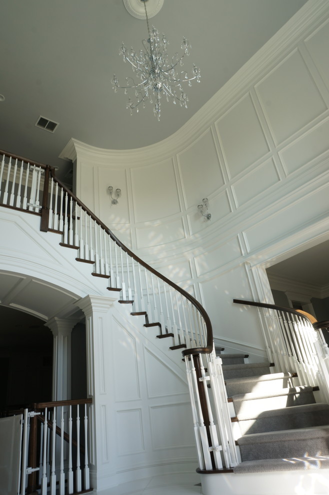 Свежая идея для дизайна: изогнутая лестница среднего размера в стиле неоклассика (современная классика) с деревянными ступенями, крашенными деревянными подступенками и деревянными перилами - отличное фото интерьера