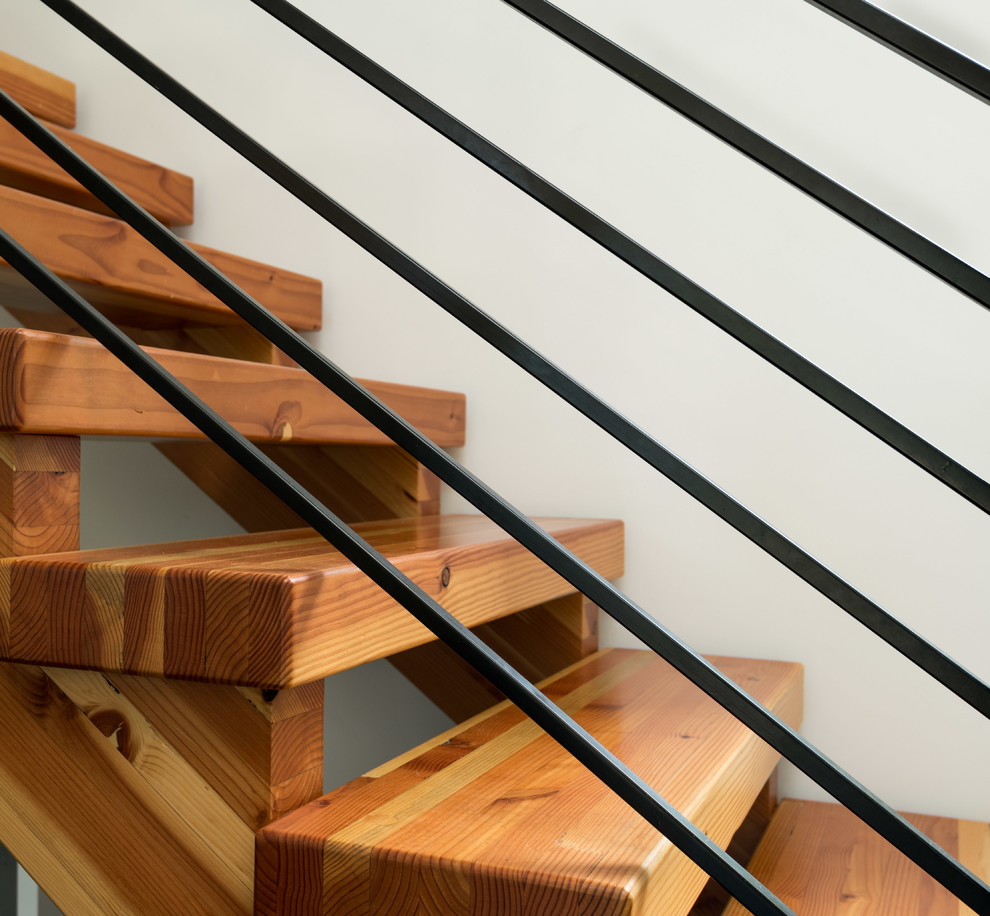 Immagine di una scala a rampa dritta scandinava di medie dimensioni con pedata in legno, parapetto in metallo e nessuna alzata