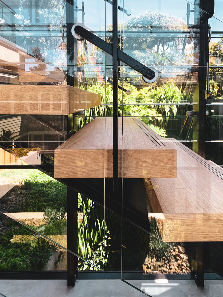 Esempio di una grande scala a rampa dritta design con pedata in legno, alzata in vetro e parapetto in materiali misti