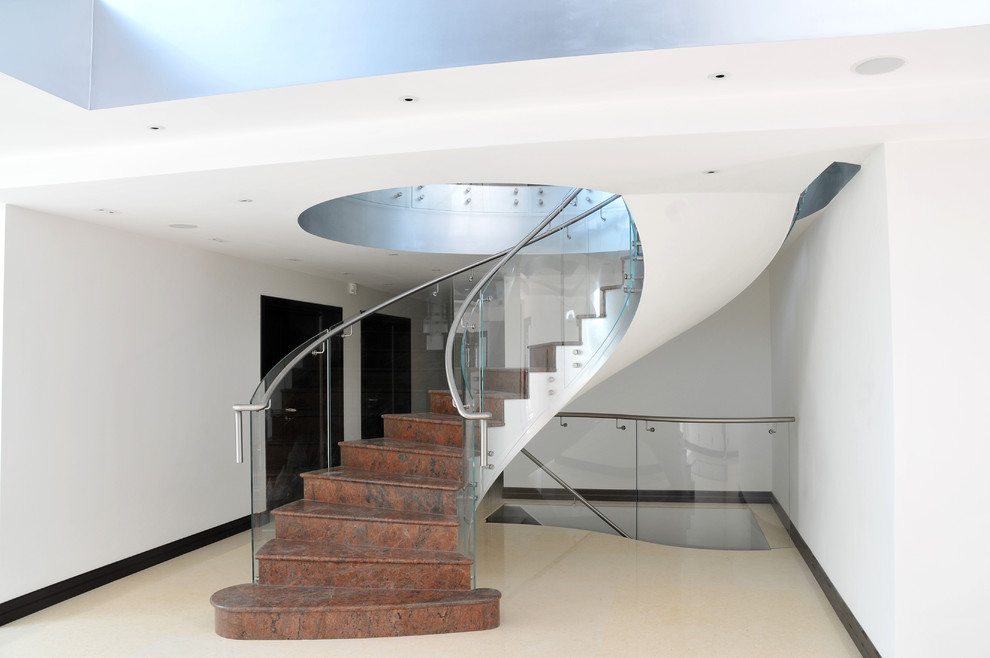 Idées déco pour un escalier courbe contemporain en marbre avec des contremarches en marbre, un garde-corps en verre et éclairage.