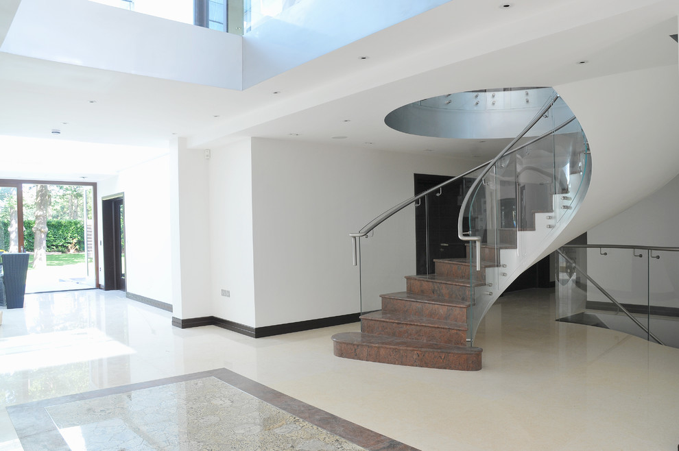 Пример оригинального дизайна: лестница в современном стиле с стеклянными перилами, мраморными ступенями и подступенками из мрамора