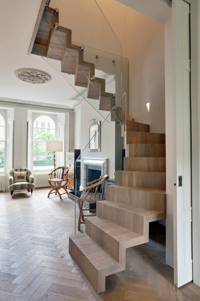 Imagen de escalera suspendida bohemia de tamaño medio con escalones de madera, contrahuellas de madera y barandilla de vidrio