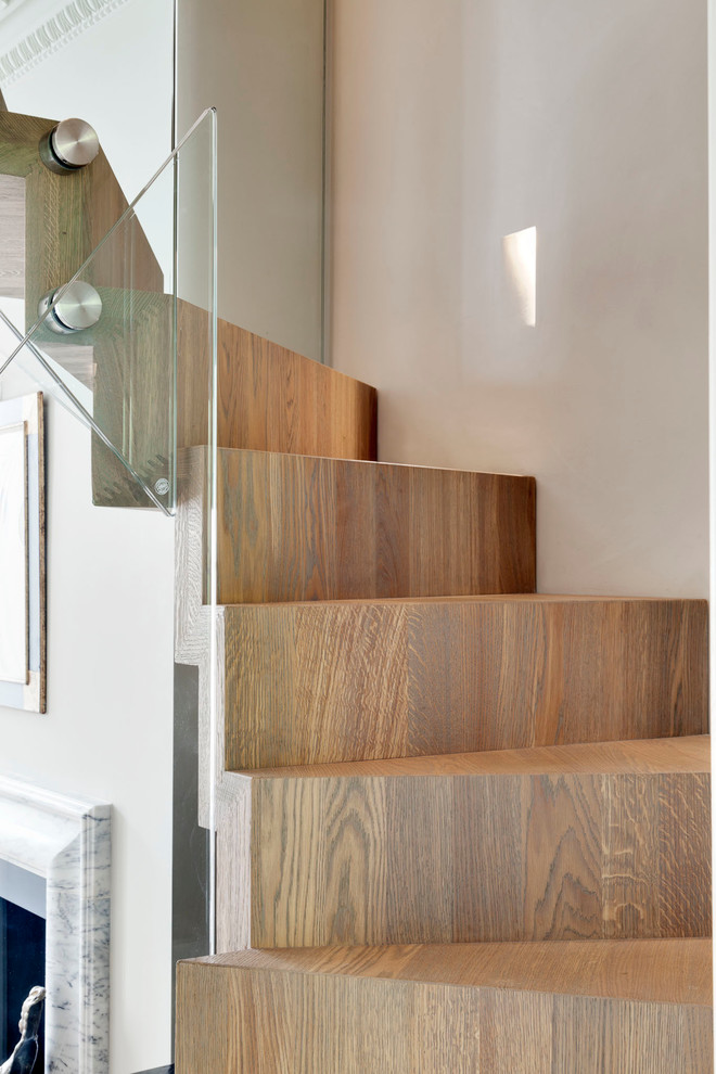 Medium sized eclectic wood floating glass railing staircase in London with wood risers and feature lighting.