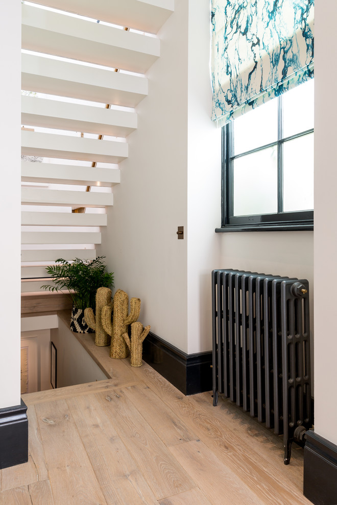 Medium sized bohemian straight metal railing staircase in London with open risers.