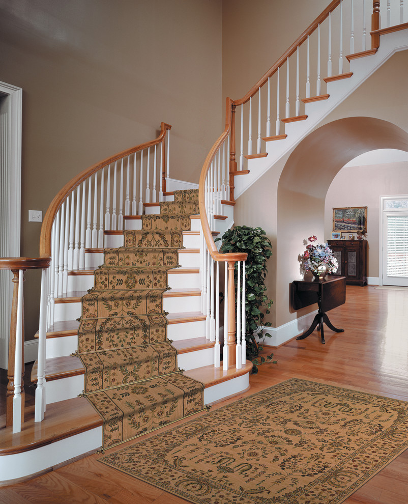 Diseño de escalera curva clásica grande con escalones de madera pintada, contrahuellas de madera y barandilla de madera