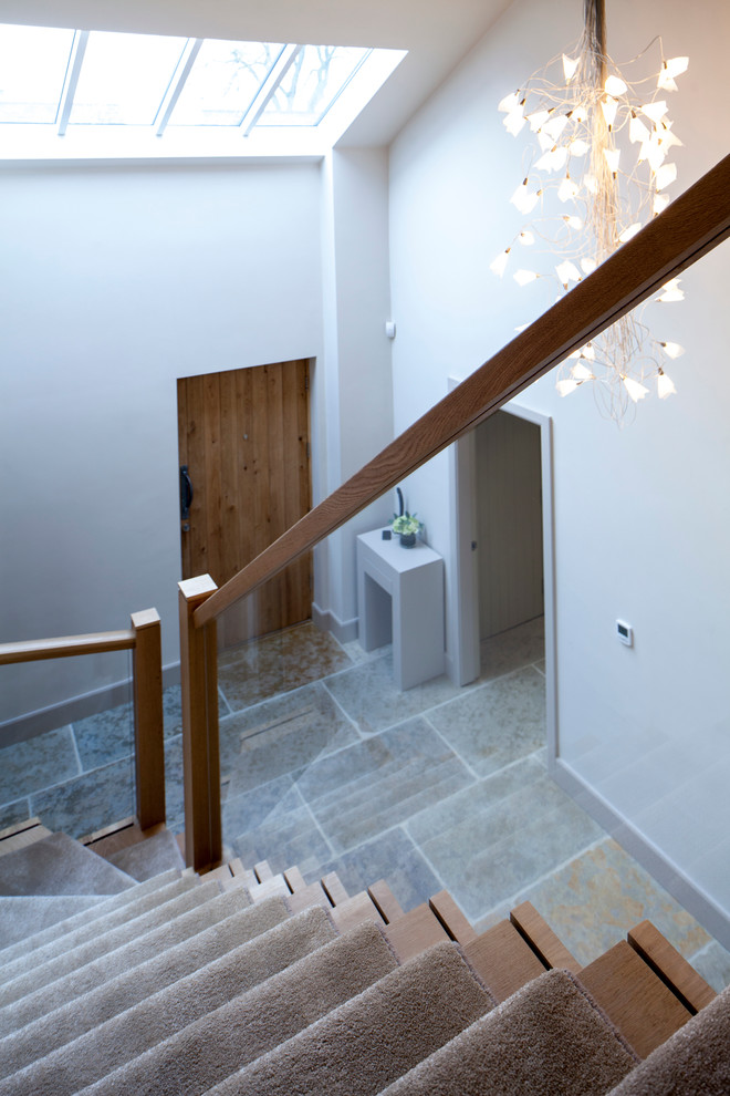 На фото: угловая деревянная лестница среднего размера в современном стиле с ступенями с ковровым покрытием с