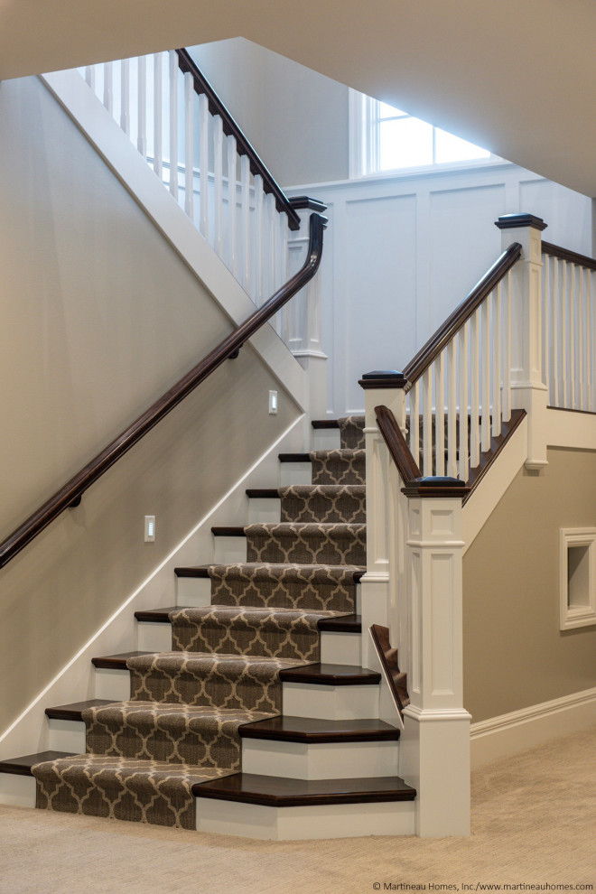 Пример оригинального дизайна: большая п-образная лестница в классическом стиле с ступенями с ковровым покрытием, ковровыми подступенками, деревянными перилами и панелями на стенах