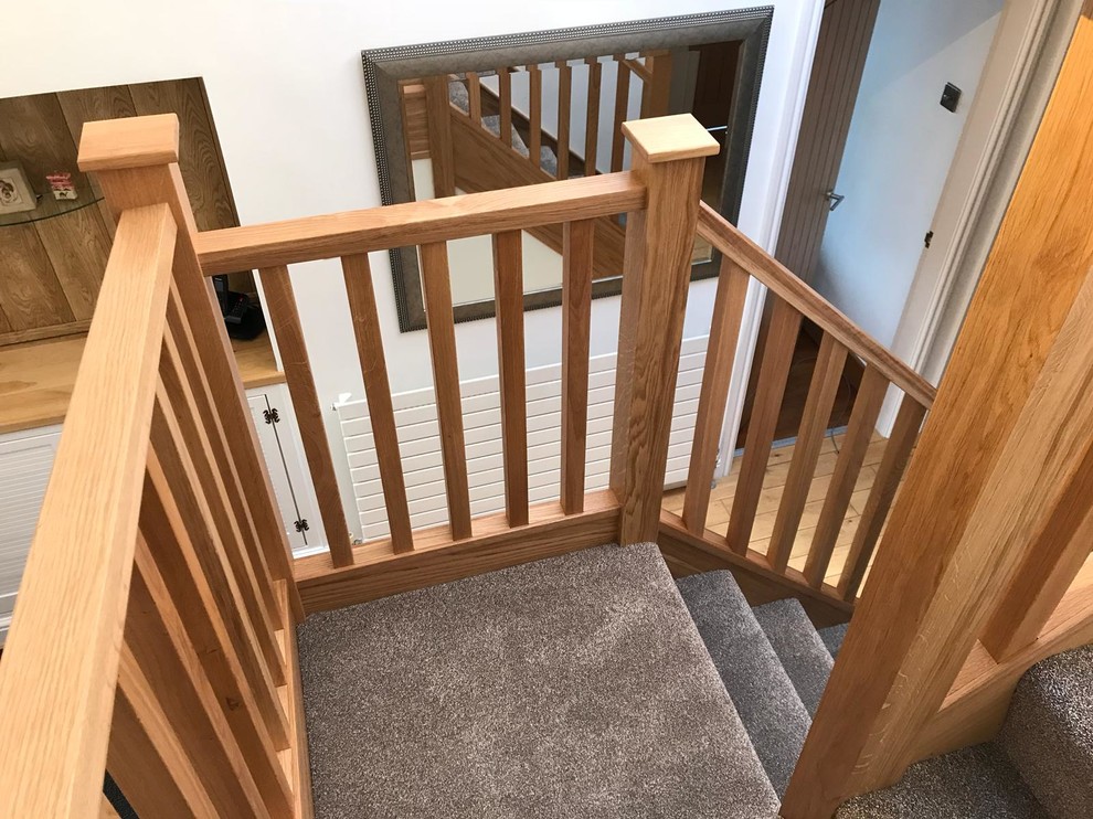 Inspiration for a medium sized contemporary carpeted u-shaped wood railing staircase in Manchester with carpeted risers.