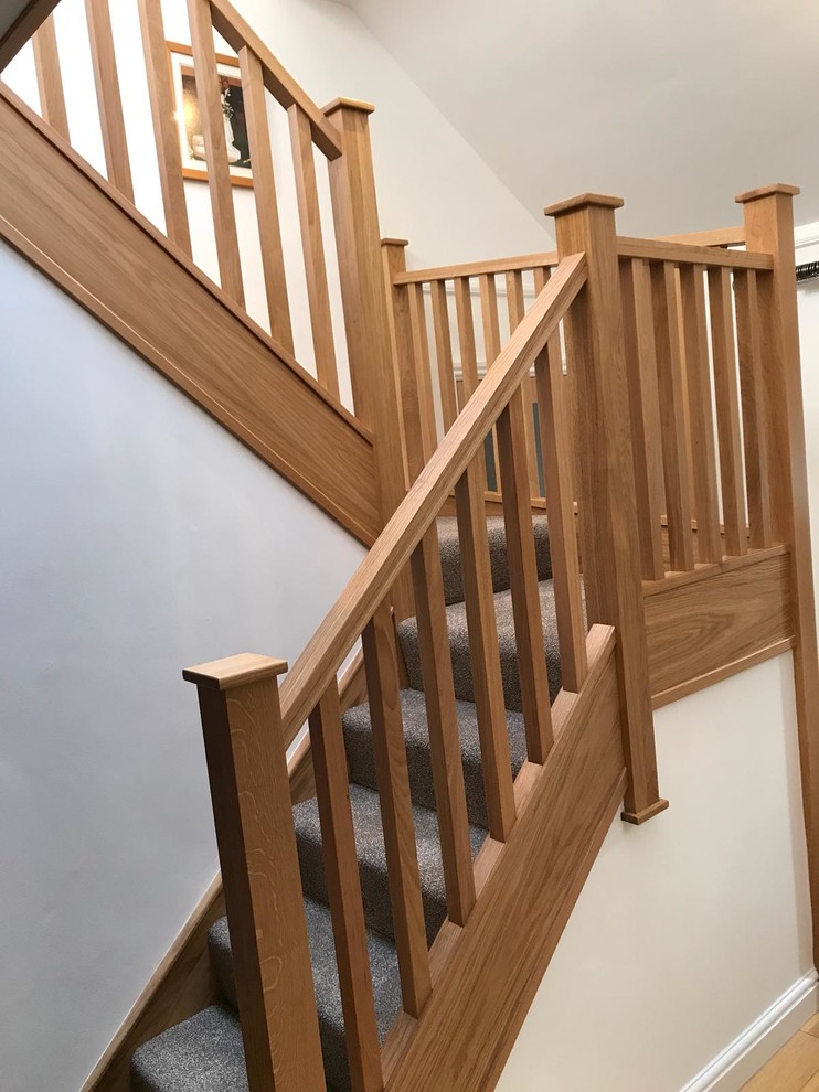 Design ideas for a medium sized contemporary carpeted u-shaped wood railing staircase in Manchester with carpeted risers.