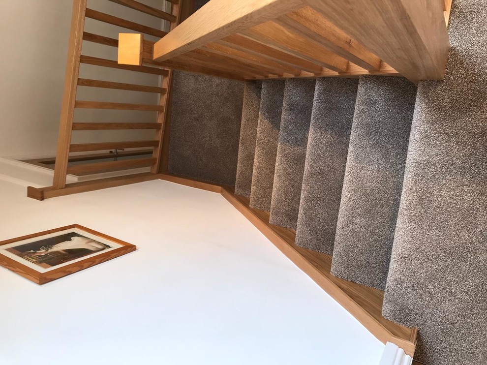 Inspiration for a medium sized contemporary carpeted u-shaped wood railing staircase in Manchester with carpeted risers.
