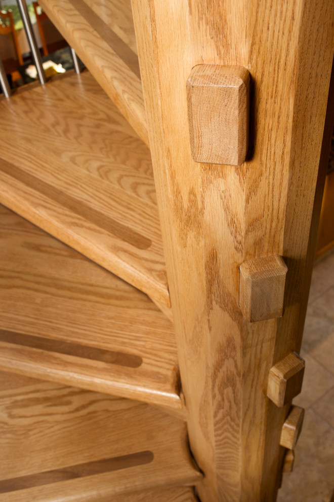 На фото: винтовая деревянная лестница в стиле кантри с деревянными ступенями и перилами из смешанных материалов с