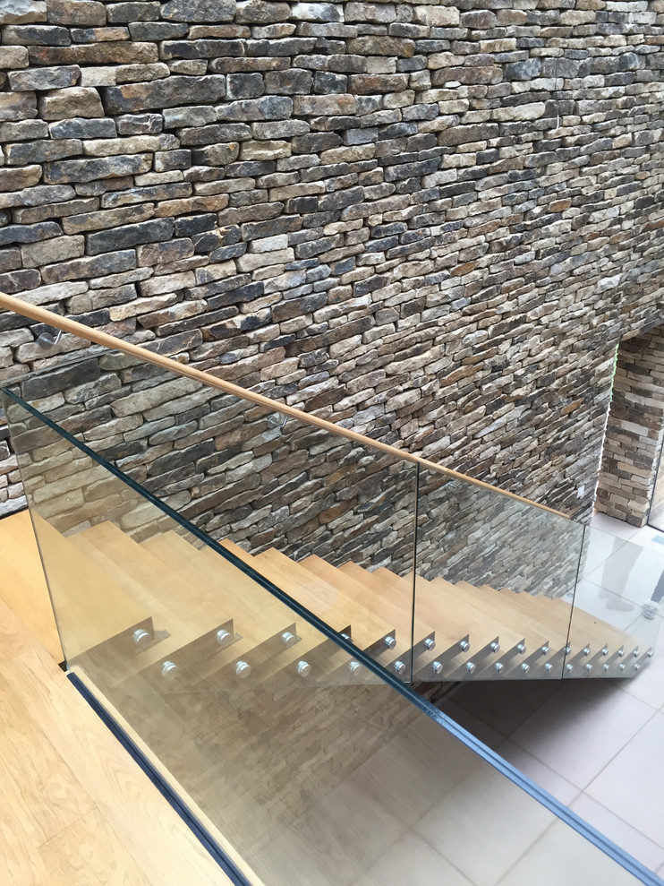This is an example of a medium sized contemporary wood straight glass railing staircase in Other with open risers.