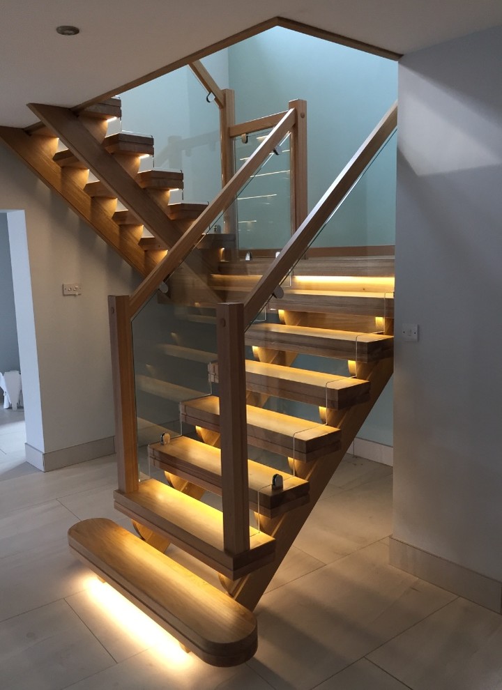 На фото: п-образная лестница среднего размера в современном стиле с деревянными ступенями и стеклянными перилами