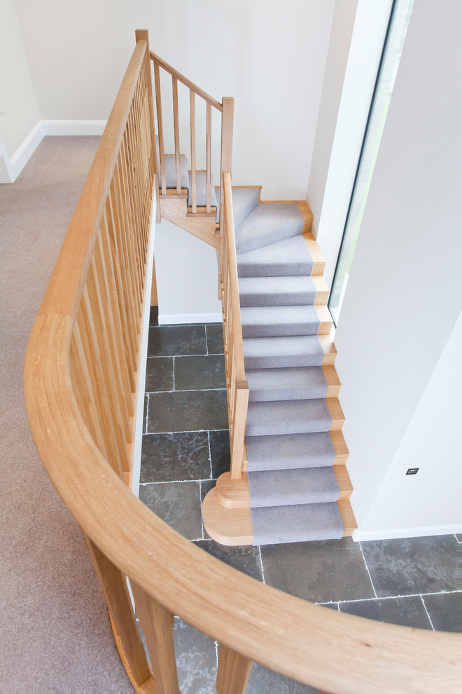 Foto de escalera curva moderna grande con escalones de madera, contrahuellas de madera y barandilla de madera