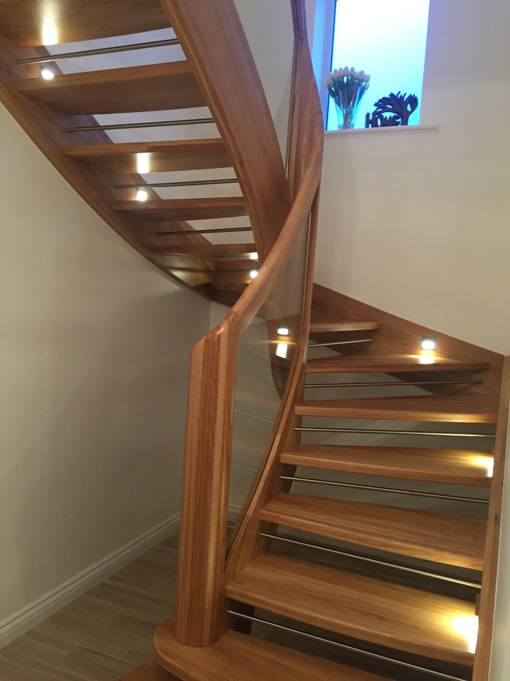 Example of a small trendy wooden u-shaped glass railing staircase design in Manchester with metal risers