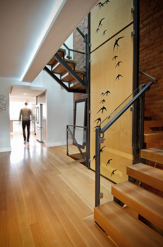На фото: изогнутая лестница среднего размера в стиле лофт с деревянными ступенями и металлическими перилами без подступенок с