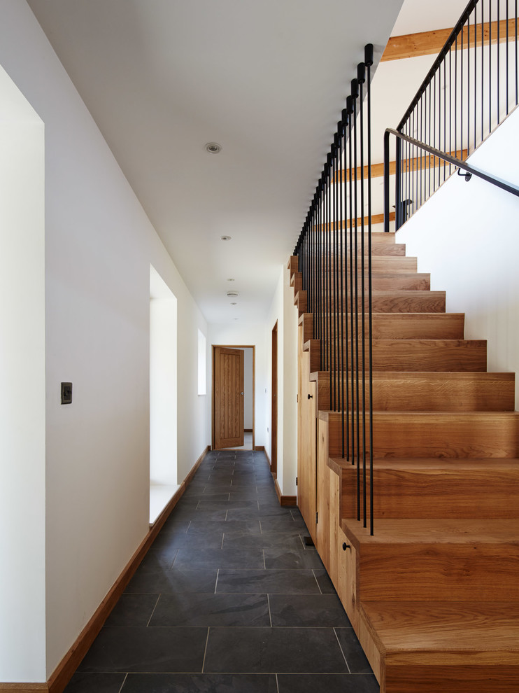 Medium sized contemporary wood straight metal railing staircase in Other with wood risers and under stair storage.