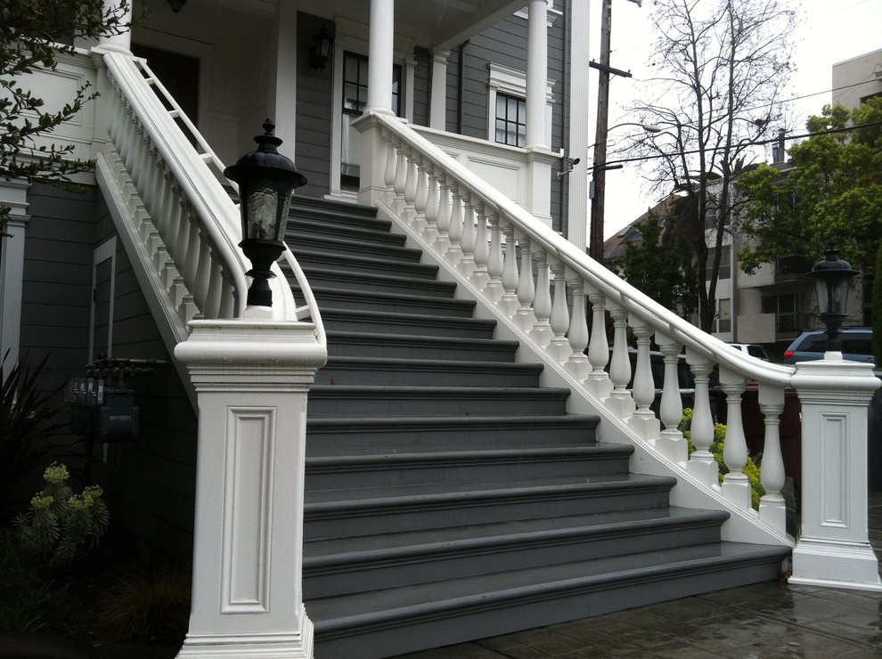 На фото: огромная изогнутая лестница с крашенными деревянными ступенями и крашенными деревянными подступенками с
