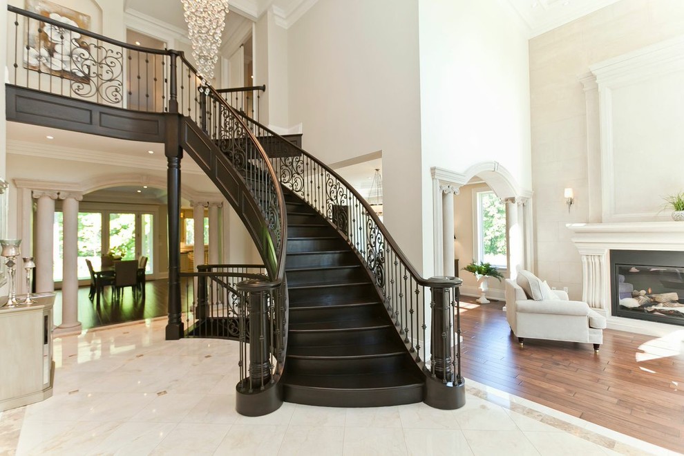 This is an example of an expansive traditional painted wood curved staircase in Toronto with painted wood risers.