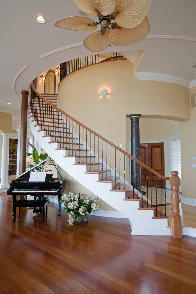 Foto de escalera curva clásica renovada grande con escalones de madera, contrahuellas de madera pintada y barandilla de varios materiales