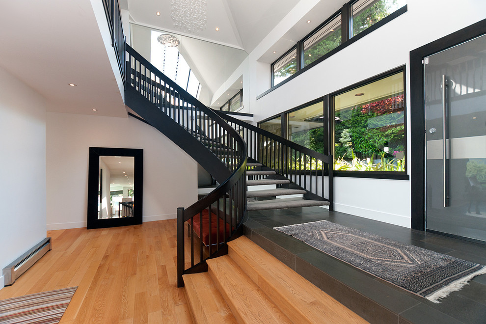 Стильный дизайн: большая изогнутая лестница в современном стиле с ступенями с ковровым покрытием без подступенок - последний тренд