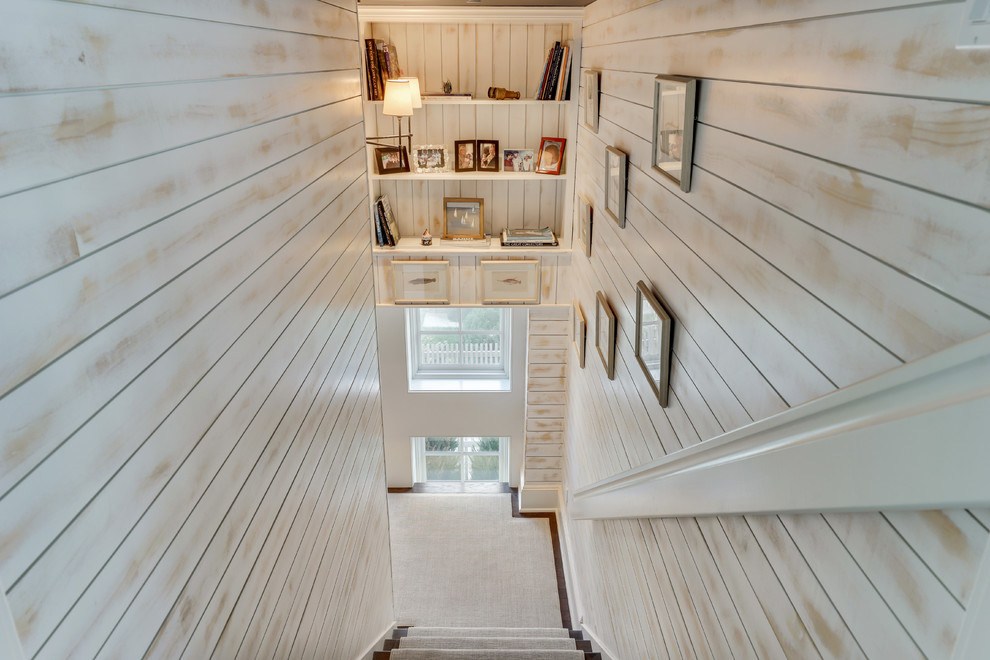 На фото: угловая лестница среднего размера с ступенями с ковровым покрытием, ковровыми подступенками и деревянными перилами