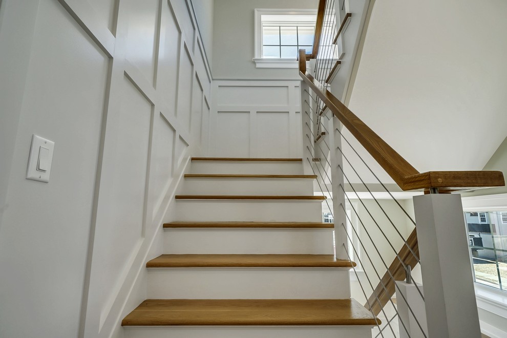 На фото: угловая деревянная лестница в морском стиле с деревянными ступенями и перилами из тросов