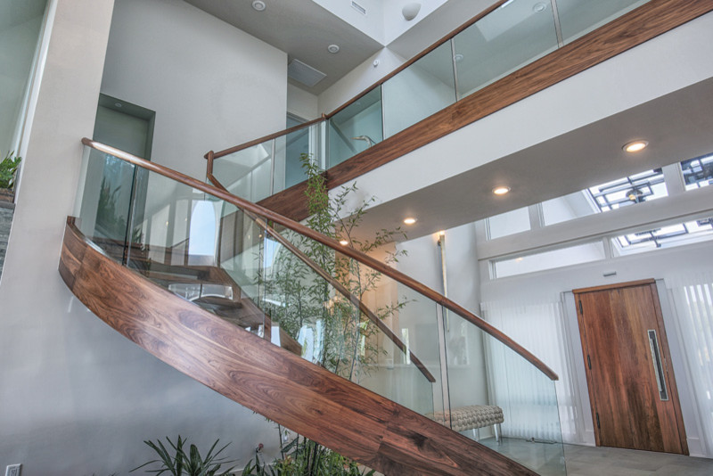 Large modern wood curved wood railing staircase in Other with open risers.