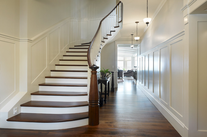 Imagen de escalera curva clásica de tamaño medio con escalones de madera, contrahuellas de madera pintada y barandilla de madera