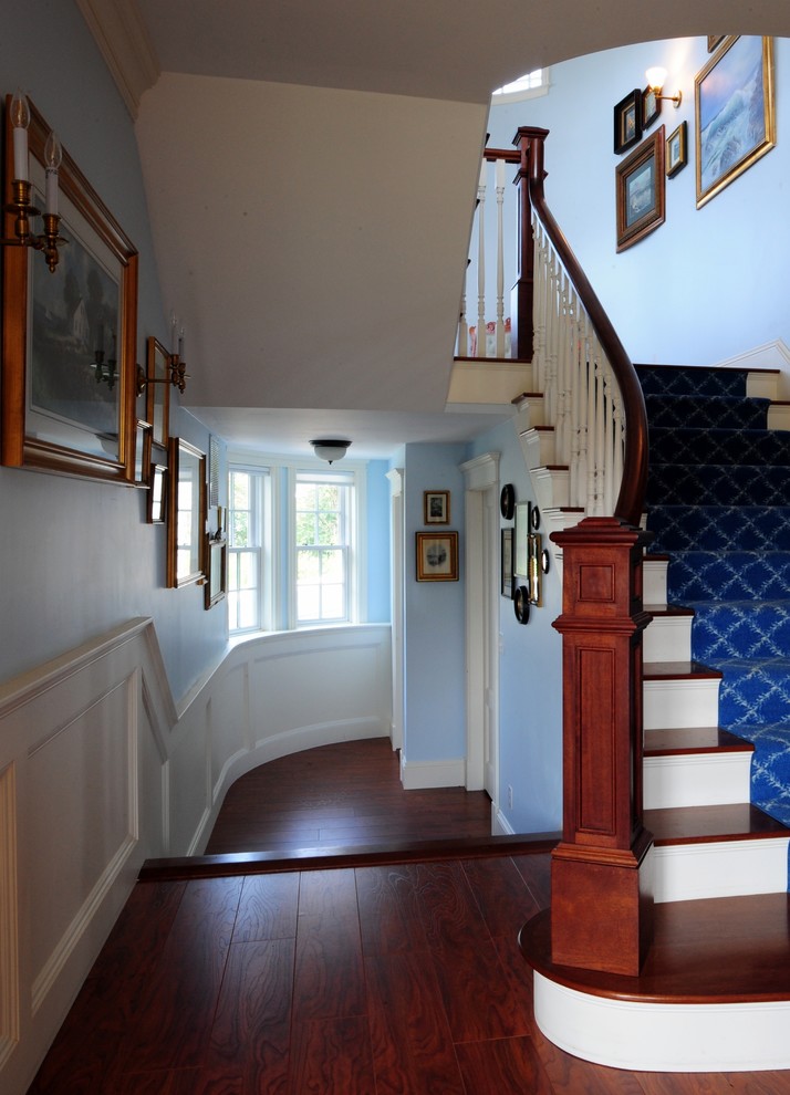 На фото: большая п-образная лестница в классическом стиле с деревянными ступенями и крашенными деревянными подступенками с