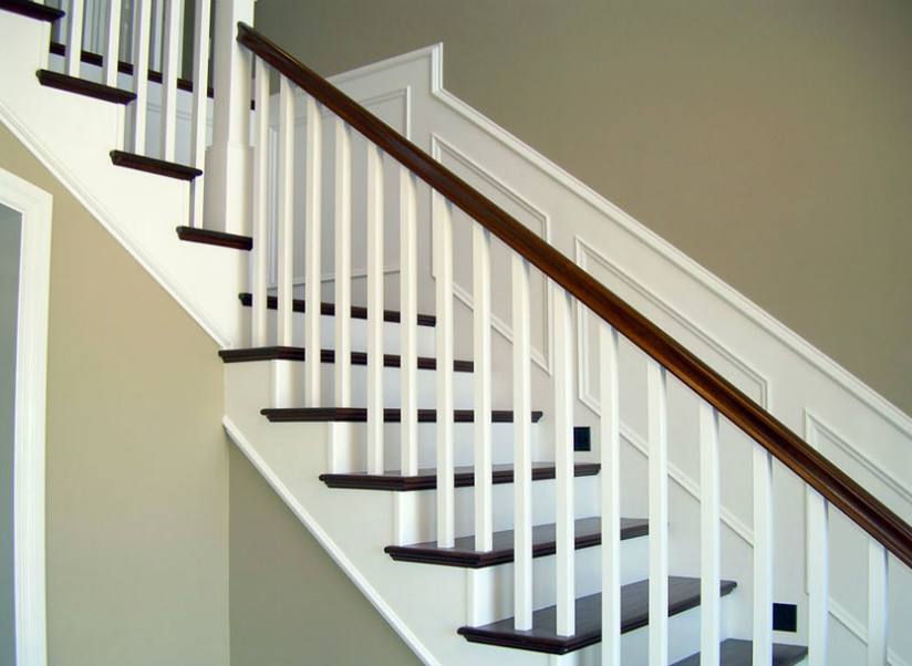 На фото: угловая лестница в классическом стиле с деревянными ступенями, крашенными деревянными подступенками, деревянными перилами и панелями на стенах