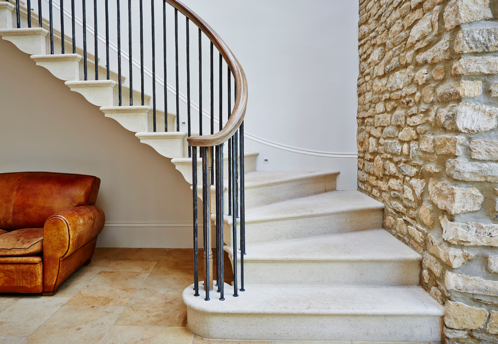 Réalisation d'un grand escalier courbe minimaliste en marbre avec des contremarches en métal.
