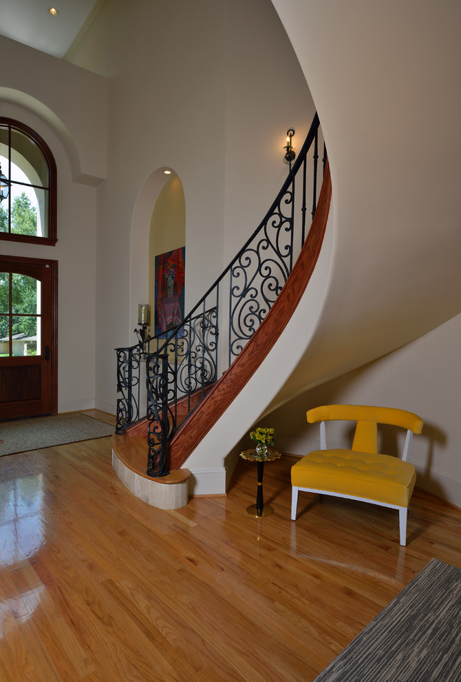 Aménagement d'un grand escalier courbe classique avec des marches en bois et des contremarches carrelées.